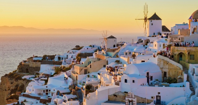 Traditional white houses and windmills at sunset in Oia, Santorini, Greece