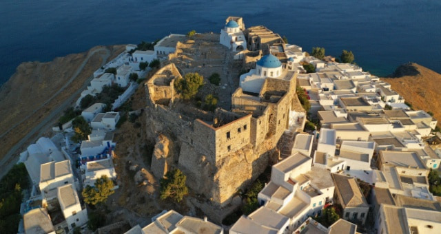 Aerial view of the Venetian Castle and blue-domed churches in Astypalea, Greece at sunset
