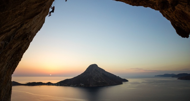 Silhouette of a person rock climbing in a large cave overlooking Telendos island in Kalymnos, Greece