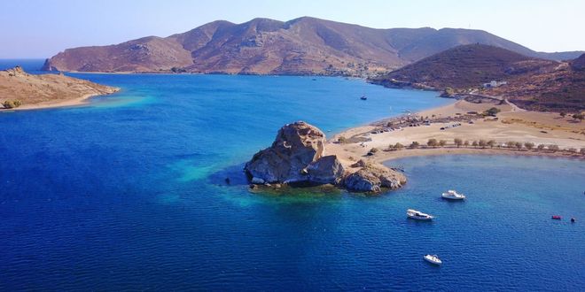 Large rock formation in the blue sea at Petra beach in Patmos, Greece