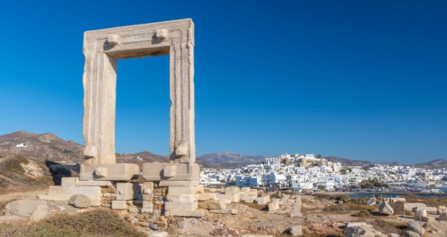The ancient marble Portara gate overlooking the white houses of Naxos Chora and the sea in Greece