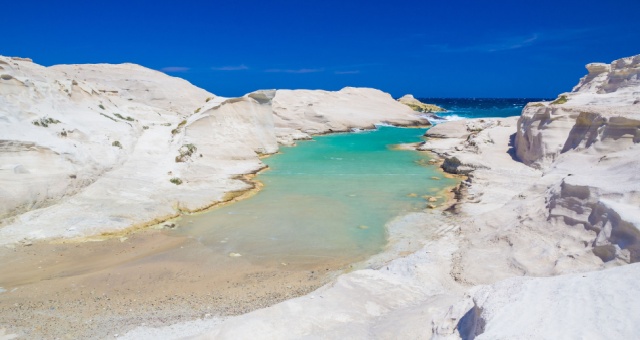 Volcanic white rock formations surrounding a bright turquoise inlet at Sarakiniko Beach in Milos, Greece