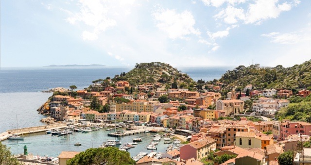 Giglio Porto with pastel houses and boats in the harbor on Giglio island, Italy
