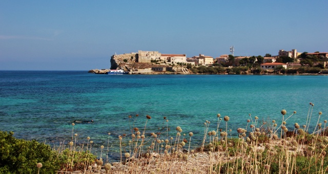 Turquoise waters and rocky coastline of Pianosa island with historic buildings in Italy
