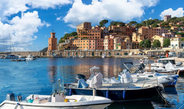 Barche ormeggiate vicino alla banchina di Rio Marina, con la cittadina e i suoi edifici storici in lontananza