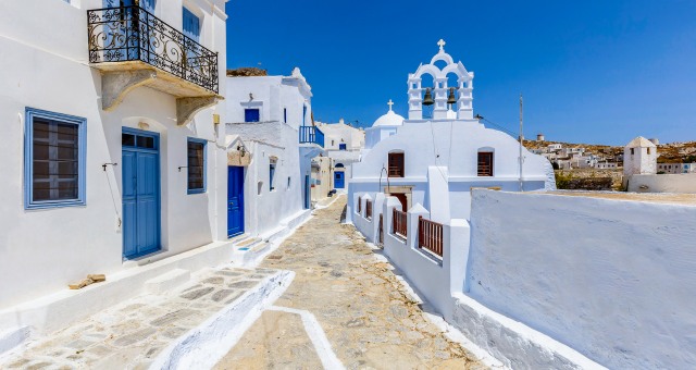 Small alley in the Chora of Amorgos, white houses, blue windows, church, balconies