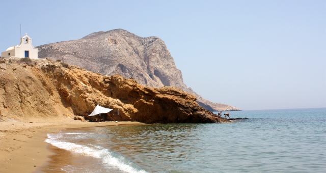 Ein Sandstrand, eine kleine Kpelle und Kalamos im Hintergrund, Anafi