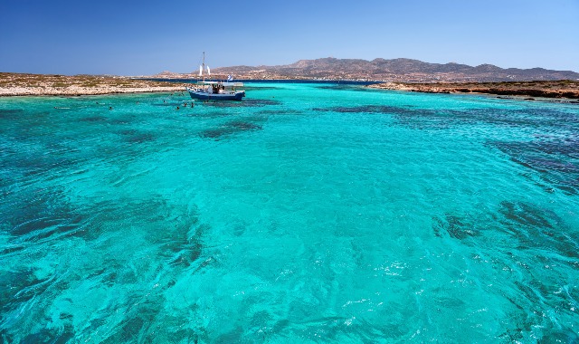 Fishing boat sailing on turquoise waters in Antiparos, Greece