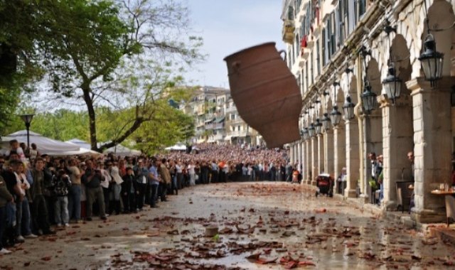 The tradition of “botides” in Corfu, Greece: locals watching a large clay pot falling from a balcony and about to hit the ground