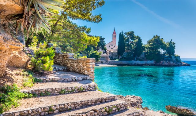 Gradini in pietra e mare turchese nella baia vicino al monastero domenicano di Bol, Croazia