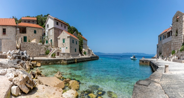 Crystal clear waters in Lučica cove surrounded by stone houses, Lastovo, Croatia