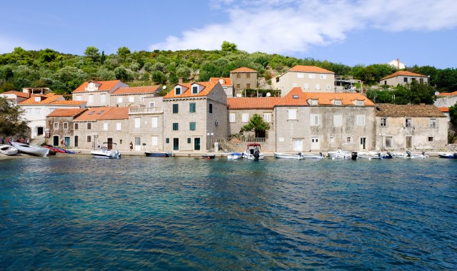 Boats docked in front of stone houses in Suđurađ, Šipan, Croatia