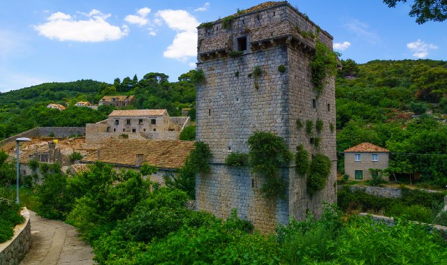 The Skočibuha Palace tower surrounded by nature and stone houses in Suđurađ, Šipan Island, Croatia