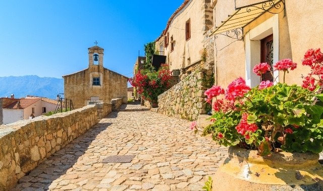 Calle empedrada con geranios y flores en San Antonio (Córcega)