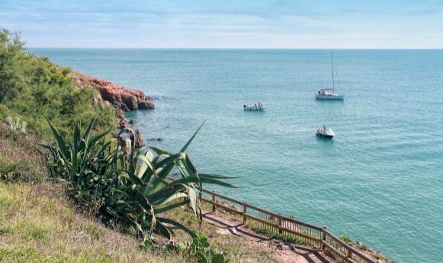 Un sentier de bord de mer à Sète avec des bateaux en arrière-plan