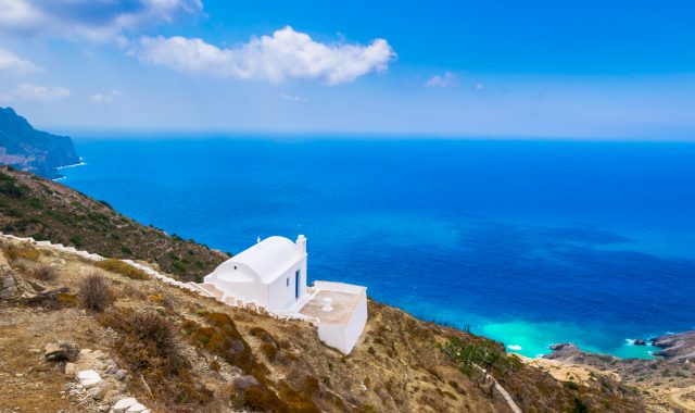 Una piccola chiesa bianca in cima a una collina che dà sul mare blu a Karpathos