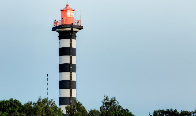 Lighthouse painted with white and black stripes at the port of Klaipėda