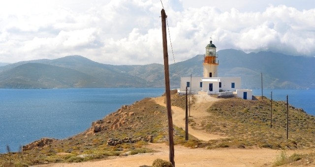 The Armenistis lighthouse on a Mykonos hill with views towards Tinos, Greece