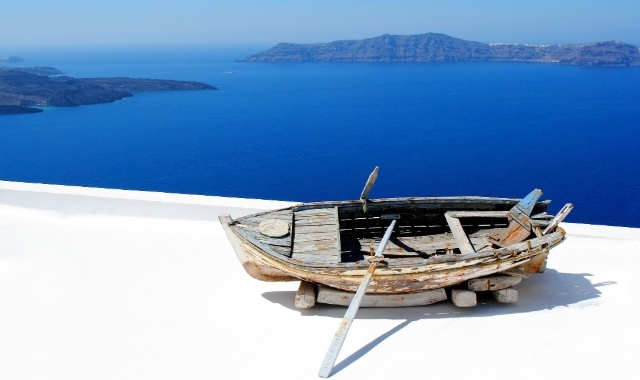 Wooden boat on a white terrace with a sea view in Santorini, Greece