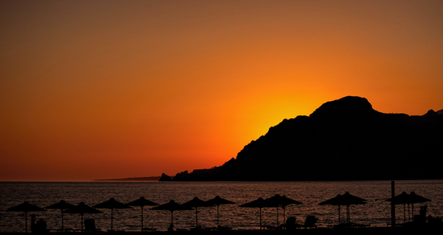 Couche de soleil sur la plage avec des parasols et des transats