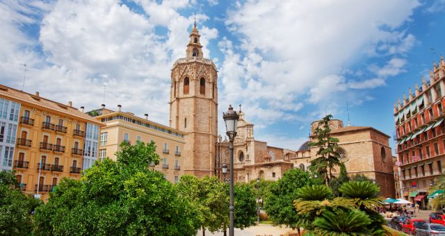 View of the Miguelete tower of the Cathedral of Valencia besides colorful historic buildings, Spain