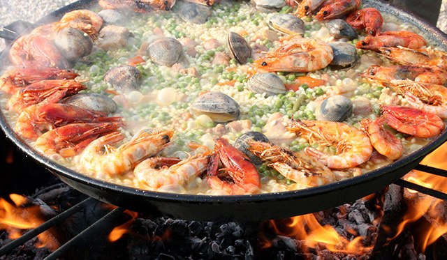 Traditional Seafood paella being cooked in a large pan over a fire in Valencia, Spain